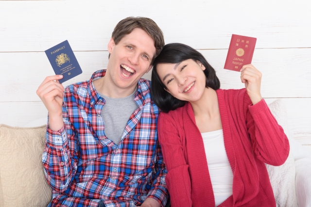 それぞれの国のパスポートを持って笑う国際恋愛カップル